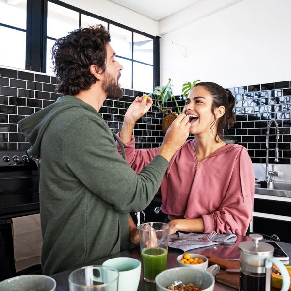 Couple laughing together while making breakfast in a modern kitchen