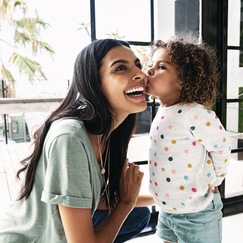 Mother kissing her young daughter