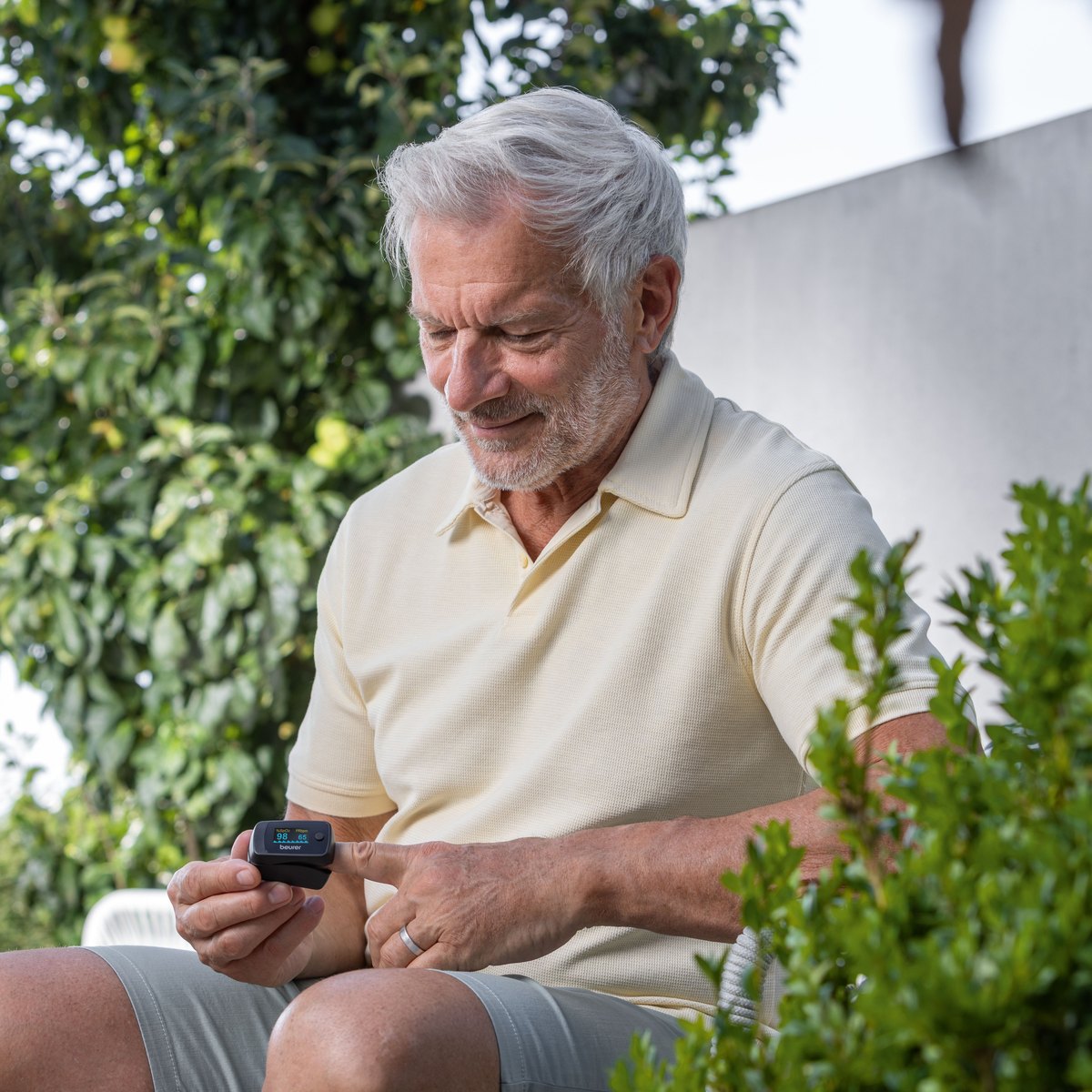 Man in a garden reading his oxygen level on a Beurer pulse oximeter