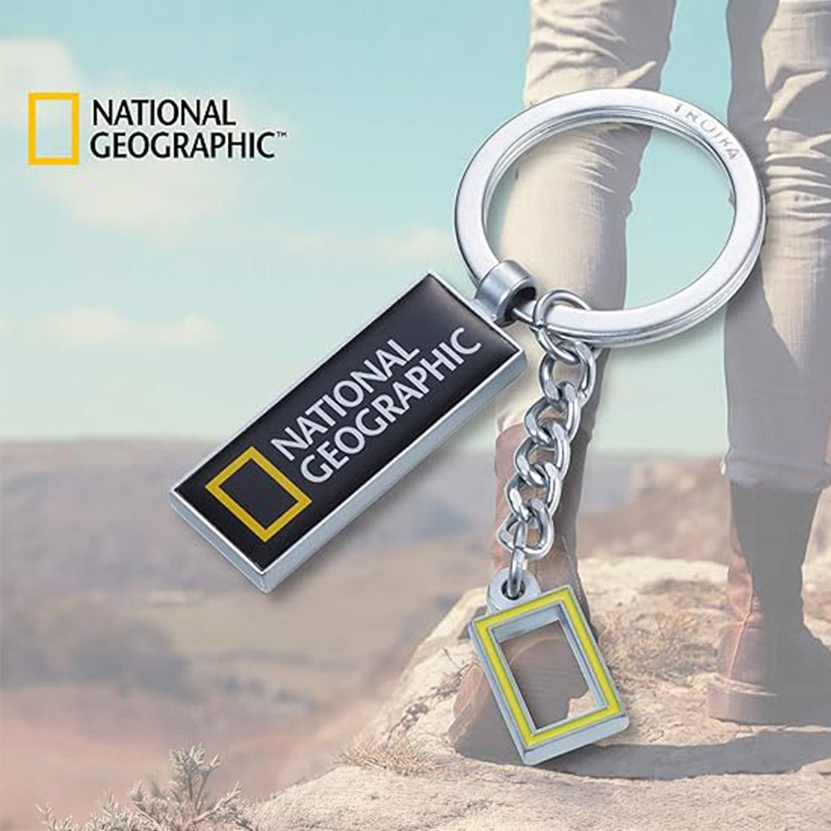 TROIKA National Geographic keyring against an outdoor hiking scene
