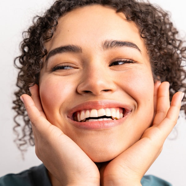 Smiling woman with clear skin, hands framing her face