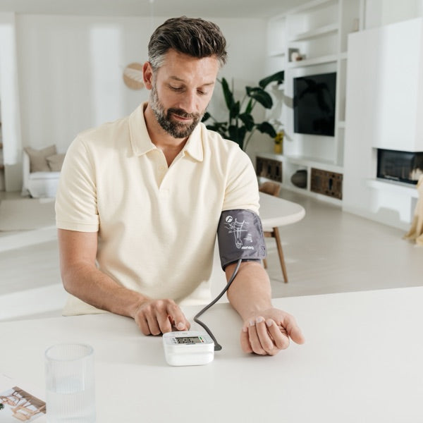 Man checking his blood pressure at home with a Beurer upper-arm monitor